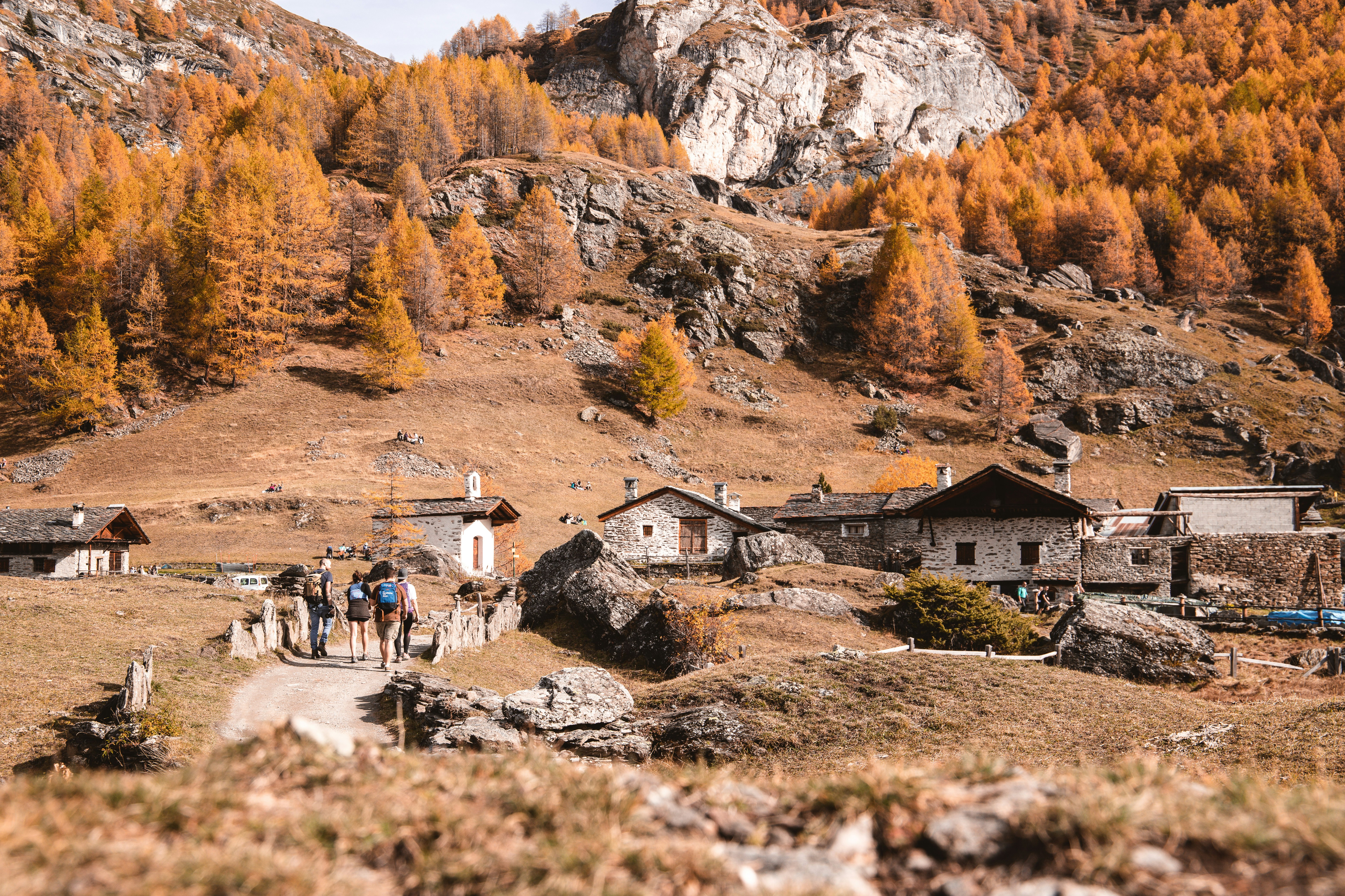 people walking on dirt road near brown and gray mountains during daytime